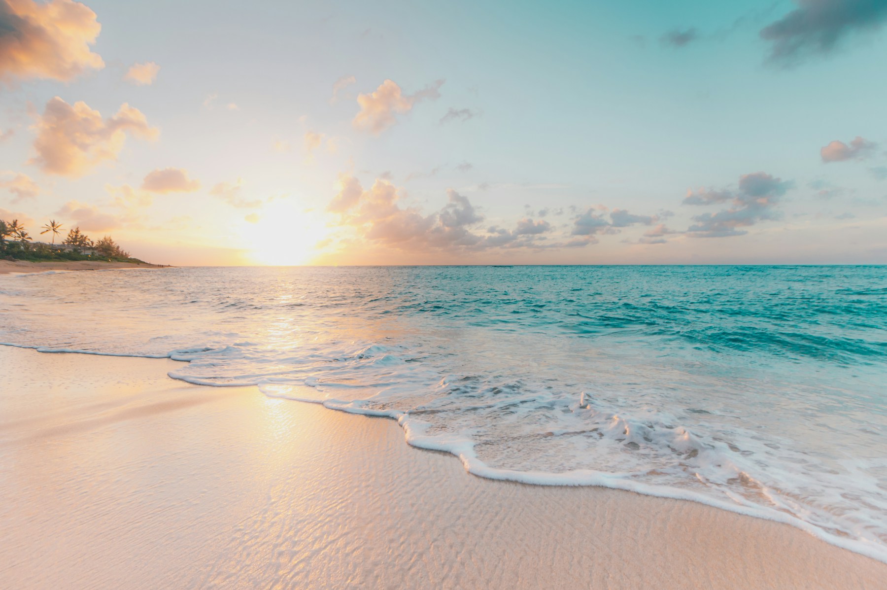 Türkisblaues Meer und ein heller Sandstrand im Abendlicht
